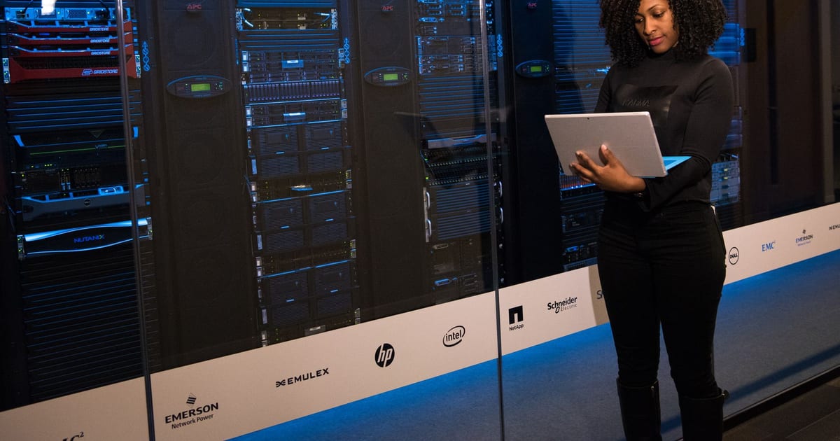 Engineer working on a laptop beside server racks in a data centre