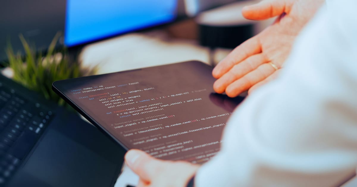 Software developer analysing code on a tablet in an office workspace